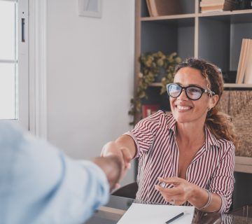 Smiling caucasian female hr manager handshake hire male candidate at job interview
